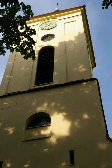 Nahaufnahme eines Kirchturms mit Uhr und Rundbogenfenstern.