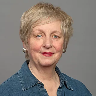 Lächelnde Frau mit kurzen blonden Haaren und rotem Lippenstift.