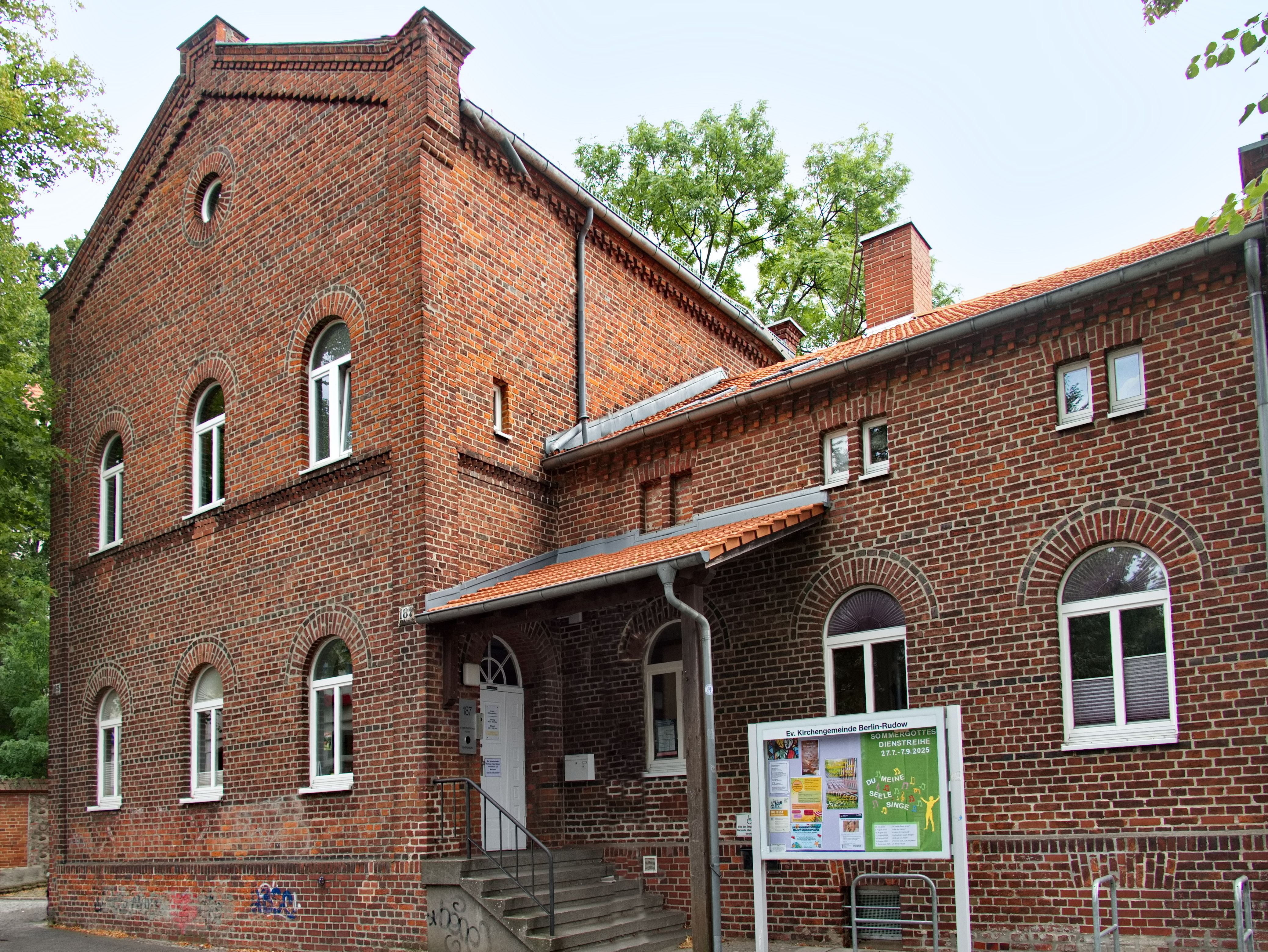 Alte Steinkirche mit rotem Dach und hohem Glockenturm.