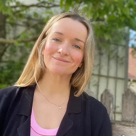 Porträt einer blonden Frau mit Nasenring, lächelnd.
